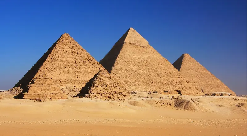 The three Great Pyramids of Giza rising from the desert under a clear blue sky